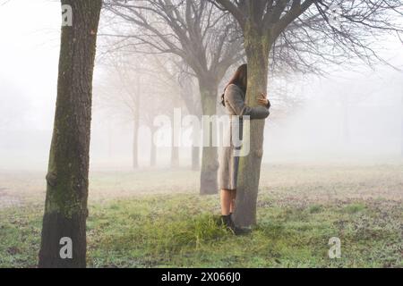 femme embrasse avec amour le tronc d'un arbre symbole de la vie, concept abstrait Banque D'Images