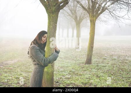 la femme embrasse doucement le tronc d'un arbre symbolisant le sang-vivant, concept abstrait Banque D'Images