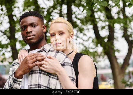 Un couple multiculturel heureux, un homme afro-américain et une femme caucasienne, partageant un moment tendre en plein air dans un parc. Banque D'Images