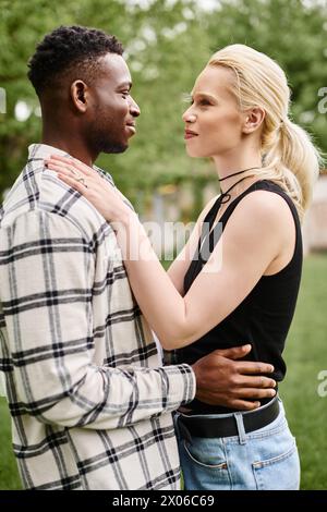 Un couple multiculturel heureux, un homme afro-américain et une femme caucasienne, debout ensemble dehors dans un parc. Banque D'Images