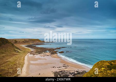 Sunnyside Beach Cullen Ecosse plage de sable avec des rochers et le Moray Firth avec une mer calme Banque D'Images