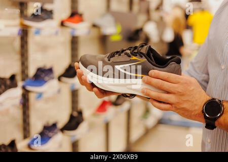 Gros plan de l'acheteur d'homme choisissant de nouvelles baskets au magasin de sport Banque D'Images