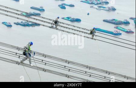 WUHU, CHINE - 10 AVRIL 2024 - des agents de maintenance inspectent le canal kV de À800 sur le fleuve Yangtsé à plus de 270 mètres d'altitude à Wuhu Banque D'Images