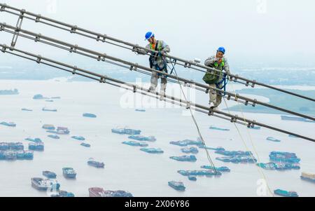 WUHU, CHINE - 10 AVRIL 2024 - des agents de maintenance inspectent le canal kV de À800 sur le fleuve Yangtsé à plus de 270 mètres d'altitude à Wuhu Banque D'Images