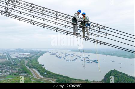 WUHU, CHINE - 10 AVRIL 2024 - des agents de maintenance inspectent le canal kV de À800 sur le fleuve Yangtsé à plus de 270 mètres d'altitude à Wuhu Banque D'Images