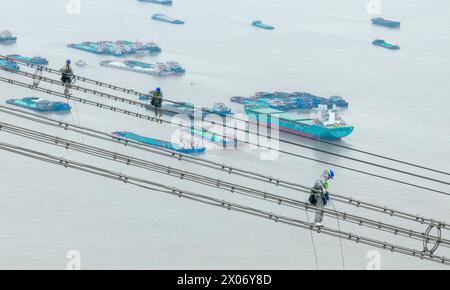 WUHU, CHINE - 10 AVRIL 2024 - des agents de maintenance inspectent le canal kV de À800 sur le fleuve Yangtsé à plus de 270 mètres d'altitude à Wuhu Banque D'Images