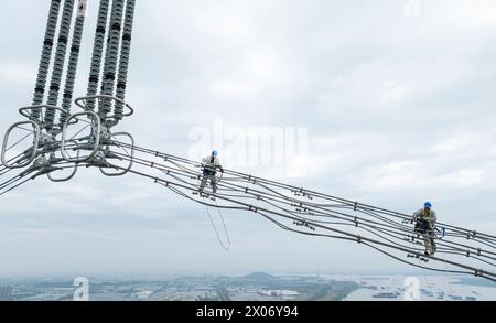 WUHU, CHINE - 10 AVRIL 2024 - des agents de maintenance inspectent le canal kV de À800 sur le fleuve Yangtsé à plus de 270 mètres d'altitude à Wuhu Banque D'Images