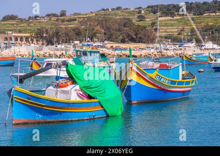 Marsaxlokk, Malte - 23 mars 2022 : deux bateaux de pêche traditionnels maltais appelés Luzzu amarrés dans le port de Marsaxlokk. Banque D'Images