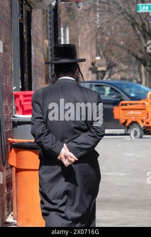 Une photo anonyme générique d'un homme juif hassidique s'éloignant de la caméra avec ses mains derrière le dos. À Brooklyn, New York. Banque D'Images