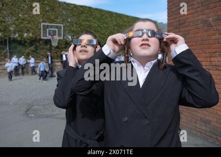 Deux garçons juifs hassidiques regardent l'éclipse solaire de 2024 dans leur cour d'école dans le comté de Rockland, New York. Banque D'Images