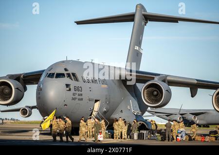 Les aviateurs américains du 21e escadron de transport aérien accueillent et déchargent l'équipement d'un C-17 Globemaster III sur la ligne de vol de la base aérienne de Travis Banque D'Images