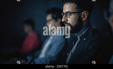 Beau étudiant Smart Male, étudiant à l'université avec divers camarades de classe multiethniques. Il travaille sur ordinateur de bureau à l'université. Application de ses connaissances en écriture de code, développement de logiciels. Banque D'Images