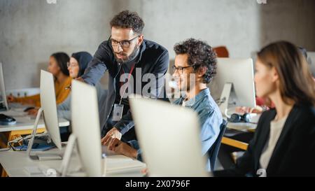 Conférencier aide Scholar avec Project, conseillant sur leur travail. Enseignant donnant des leçons à divers groupes multiethniques d'étudiants féminins et masculins dans College Room, enseignant de nouvelles compétences académiques sur un ordinateur. Banque D'Images