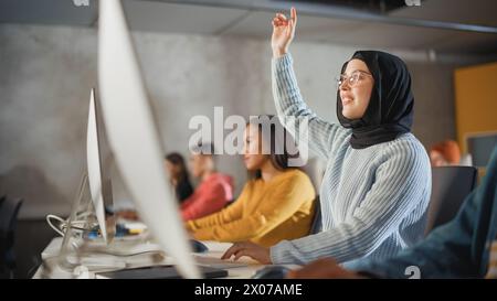 Étudiante musulmane intelligente en Hijab étudiant à l'université avec divers camarades de classe multiethniques. Elle lève la main et pose une question au professeur. Appliquer ses connaissances pour acquérir des compétences académiques en classe Banque D'Images