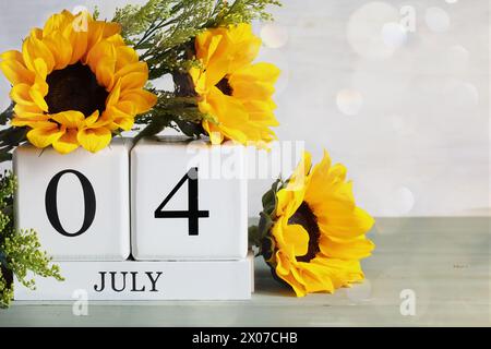 Jour de l'indépendance des États-Unis. Blocs de calendrier en bois blanc avec la date du 4 juillet et beau bouquet de tournesol avec bokeh. Mise au point sélective. Banque D'Images