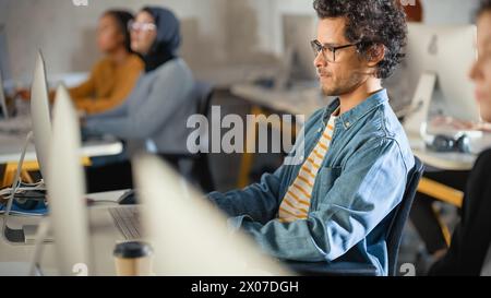Beau étudiant Smart Male, étudiant à l'université avec divers camarades de classe multiethniques. Il travaille sur ordinateur de bureau à l'université. Appliquer ses connaissances pour acquérir des compétences académiques en classe. Banque D'Images