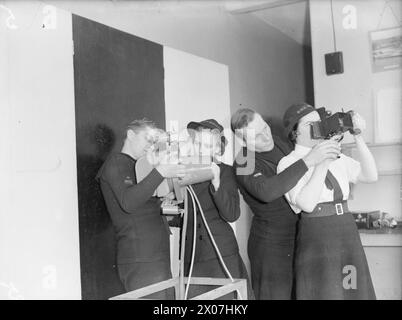 ASSISTANTS PHOTOGRAPHIQUES WREN. 19 JANVIER 1942, ROYAL NAVY AIR STATION DONIBRISTLE, FIFE. ÉCRIT EN FORMATION POUR ÊTRE ASSISTANTS PHOTOGRAPHIQUES. - Bluejackets de la section photographique Fleet Air Arm montrant aux élèves photographes de Wren les différents types de caméras aériennes utilisées Banque D'Images