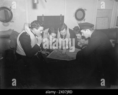 À BORD DU HMS VICTORIOUS. FÉVRIER 1942, EN MER DANS L'ATLANTIQUE NORD ET AU LARGE DES CÔTES NORVÉGIENNES. LORS DE L'OFFENSIVE CONTRE LA NAVIGATION ENNEMIE ET TOUT EN COUVRANT UN CONVOI RUSSE. - Les pilotes et les observateurs de la Fleet Air Arm discutent de leur probable ligne d'attaque pendant qu'ils attendent dans la salle d'attente des pilotes et des observateurs Banque D'Images