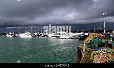 Soleil et nuages sombres au-dessus des bateaux dans le port de Torquay, à l'approche de la pluie. Banque D'Images