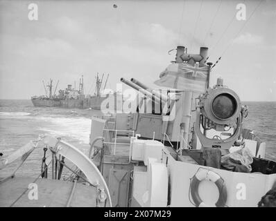 Un Liberty ship américain escorté par la Royal Navy et des avions alliés lors d'un convoi en Afrique du Nord le 14 avril 1943, photographié depuis le HM Destroyer Badsworth alors que des canons protègent contre les menaces sous-marines. Banque D'Images