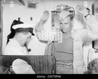 LES HOMMES DE ROMMEL N'AVAIENT PAS DUNKERQUE - LA ROYAL NAVY RASSEMBLE LES ALLEMANDS EN FUITE. 12 ET 13 MAI 1943, MALTE, DES FORCES NAVALES LÉGÈRES PATROUILLANT DANS LES PASSAGES SICILIENS AU LARGE DES CÔTES DE TUNIS EMPÊCHÈRENT ROMMEL AFRIKA KORPS DE FAIRE UNE ÉVACUATION DE DUNKERQUE D'AFRIQUE DU NORD. - Un prisonnier allemand fouillé dans la cabine du premier lieutenant Banque D'Images