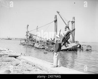 COMMENT LES FORCES AÉRIENNES ALLIÉES ONT MITRAILLÉ FERRYVILLE. 13 MAI 1943, FERRYVILLE, CHANTIER NAVAL FRANÇAIS, PRÈS DE BIZERTE. LE PORT DE FERRYVILLE A OBTENU SA PART DU BLITZ ALLIÉ PRESQUE SANS ESCALE SUR LES POINTS D’APPROVISIONNEMENT DE L’AXE QUI ONT PRÉCÉDÉ LA DÉFAITE TOTALE DE L’ALLEMAGNE ET DE L’ITALIE EN AFRIQUE. - Les restes d'un navire de munitions italien bombardé qui a été explosé causant des dégâts considérables lors d'un raid allié Banque D'Images