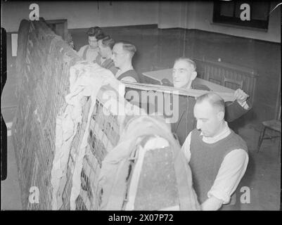 ILS SE BATTENT AUSSI QUI NE FONT QUE SE TENIR DEBOUT ET ATTENDRE : LES HOMMES DES POMPIERS NATIONAUX FONT DU TRAVAIL DE GUERRE SUPPLÉMENTAIRE, LONDRES, 1942 - les hommes des pompiers nationaux font des filets de camouflage à la caserne de Battersea Banque D'Images