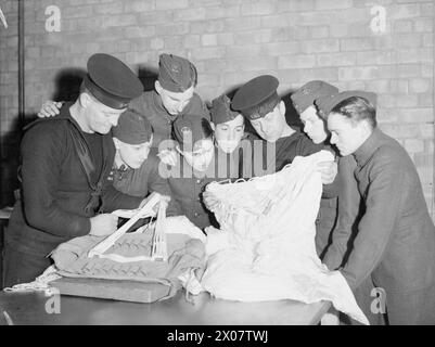 BRITISH AIRCRAFT TRAINING CORPS. LES GARÇONS VISITENT UNE STATION AÉRIENNE DE LA ROYAL NAVY 18 JANVIER 1942, STATION AÉRIENNE DE LA ROYAL NAVY DONIBRISTLE. CHAQUE DIMANCHE, LORSQUE LES CIRCONSTANCES LE PERMETTENT, LES GARÇONS DE L'ATC DES VILLES VOISINES VISITENT LA ROYAL NAVY AIR STATION. - Les packers de parachute Bluejacket montrant aux garçons de l'ATC comment emballer un parachute Banque D'Images