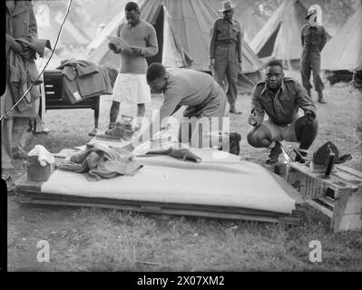 CAMP DES MARCHEURS DE LA VICTOIRE À LONDRES : HÉBERGEMENT DANS LES JARDINS DE KENSINGTON, LONDRES, ANGLETERRE, Royaume-Uni, 1946 - les hommes d'une unité d'Afrique de l'est repassent leurs vêtements devant leur camp de tentes dans les jardins de Kensington, Londres Banque D'Images