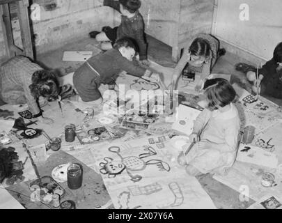 COLONIE POUR ARTISTES DE MOINS DE SIX ANS : ÉVACUÉS À DARTINGTON HALL, TOTNES, DEVON, ANGLETERRE, 1941. - Les enfants évacués à Dartington Hall à Totnes, Devon bénéficient d'un cours de peinture. Les garçons et les filles ont étalé leur travail sur le sol dans une pièce de Dartington Hall et peignent avec plaisir des images de gens Banque D'Images