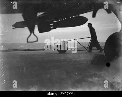 EXERCICES D'ARMEMENT AÉRIEN DE LA FLOTTE À BORD DU HMS VICTORIOUS. 1ER JANVIER 1942, EN MER AU LARGE DE HOY, PRÈS DE SCAPA. - Une Royal Marine volant une bombe de 500 lbs sur le pont de VICTORIOUS à l'aube Banque D'Images