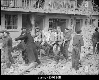 Des travailleurs de la défense civile portent une victime sur une civière au-dessus de gravats après un incident de roquette V2 dans le sud de l'Angleterre, en 1945. Banque D'Images