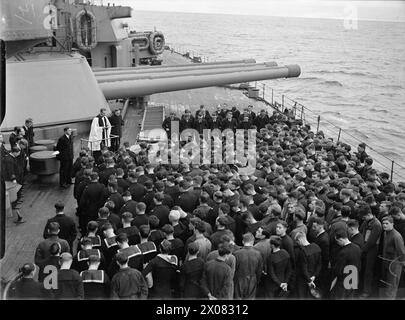 LA ROYAL NAVY PENDANT LA SECONDE GUERRE MONDIALE - Un service commémoratif pour le croiseur Marchand armé JERVIS BAY, tenu sur le pont supérieur du HMS RODNEY alors qu'il est en mer. Comparativement peu ont pu assister au service, le reste étant à leurs stations d'action, certains étant dans les tourelles des canons de 16 pouces vus dans l'image Royal Navy, RODNEY (HMS) Banque D'Images