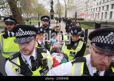 Des policiers arrêtent une personne après que des membres de Youth Demand ont jeté de la peinture rouge sur l'extérieur du bâtiment du ministère de la Défense à Londres. Date de la photo : mercredi 10 avril 2024. Banque D'Images