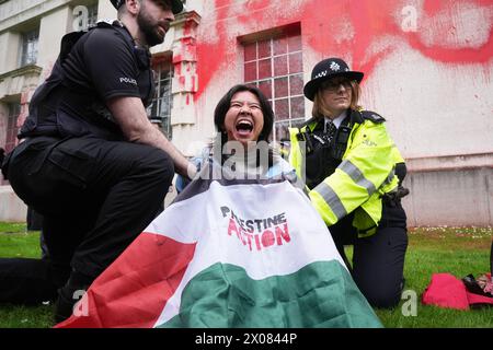 Des policiers arrêtent une personne après que des membres de Youth Demand ont jeté de la peinture rouge sur l'extérieur du bâtiment du ministère de la Défense à Londres. Date de la photo : mercredi 10 avril 2024. Banque D'Images