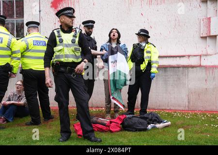 Des policiers arrêtent une personne après que des membres de Youth Demand ont jeté de la peinture rouge sur l'extérieur du bâtiment du ministère de la Défense à Londres. Date de la photo : mercredi 10 avril 2024. Banque D'Images