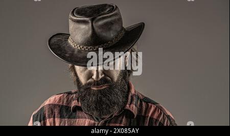 Style cow-boy. Beau jeune homme ajustant son chapeau de cow-boy. Des cowboys en chapeau. Beau macho barbu. Homme non rasé cow-boys. Cow-boy américain. Cuir Banque D'Images