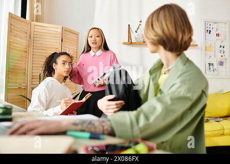 Des adolescentes multiculturelles se sont rassemblées autour d'une table, engagées dans l'étude et la construction d'amitiés. Banque D'Images