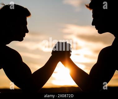 Silhouette de mains qui rivalisent en force. Rivalité, gros plan de lutte de bras mâle. Hommes mesurant les forces, les bras. Deux hommes lutte bras. Rivalité, vs Banque D'Images