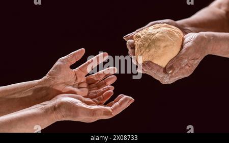 Aider les sans-abri. Femme donnant aux pauvres sans-abri des morceaux de pain, des dons, gros plan. Les mains de la vieille femme tenant un morceau de pain. Isolé sur Banque D'Images