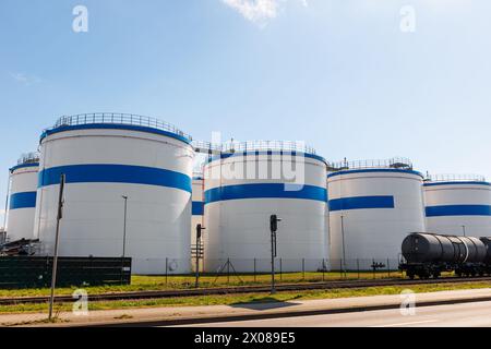 Rangée de nombreux grands réservoirs blancs de stockage de carburant industriel fond bleu clair de ciel le jour ensoleillé. Installations de dépôt de liquides de raffinerie de stockage de pétrole. Produit dangereux pour l'énergie Banque D'Images