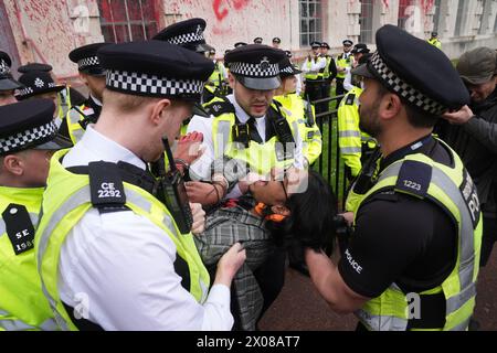 Des policiers arrêtent une personne après que des membres de Youth Demand ont jeté de la peinture rouge sur l'extérieur du bâtiment du ministère de la Défense à Londres. Date de la photo : mercredi 10 avril 2024. Banque D'Images