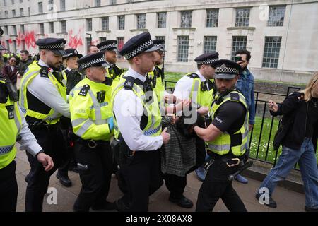Des policiers arrêtent une personne après que des membres de Youth Demand ont jeté de la peinture rouge sur l'extérieur du bâtiment du ministère de la Défense à Londres. Date de la photo : mercredi 10 avril 2024. Banque D'Images