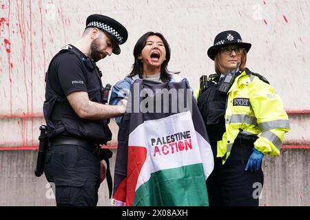 Des policiers arrêtent une personne après que des membres de Youth Demand ont jeté de la peinture rouge sur l'extérieur du bâtiment du ministère de la Défense à Londres. Date de la photo : mercredi 10 avril 2024. Banque D'Images