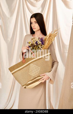 Une jeune femme aux longs cheveux bruns tient joyeusement un panier débordant de fleurs vibrantes, incarnant une humeur estivale. Banque D'Images