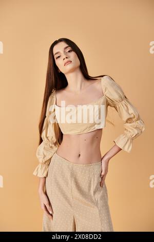 Une jeune femme aux longs cheveux bruns respire les vibrations estivales dans un short top élégant et un pantalon à larges jambes, frappant une pose dans un cadre de studio. Banque D'Images