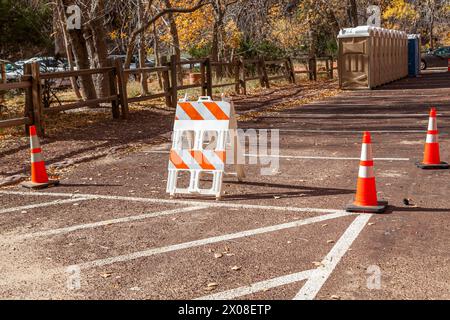 Des cônes de sécurité et une barricade bloquent les aires de stationnement à proximité des toilettes mobiles de la zone de stationnement Narrows du parc national de Zion, Utah. Banque D'Images