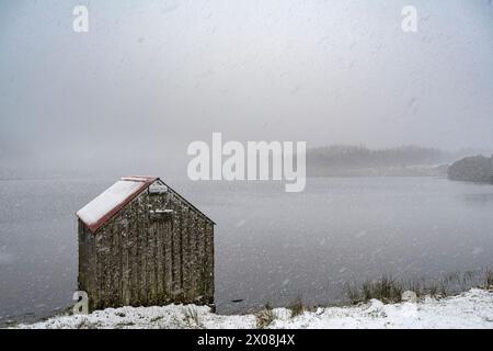 La neige tombe sur le Loch laide près d'Abriachan dans les Highlands écossais le matin du 4 avril 2024. Banque D'Images