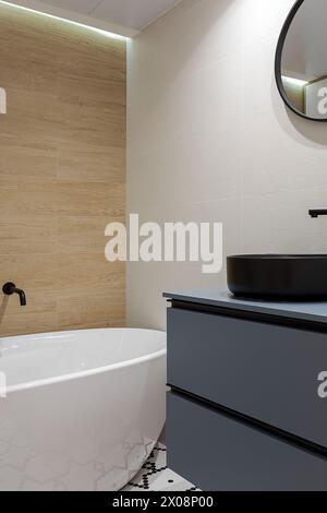 Salle de bains intérieure moderne avec baignoire sur pied, accents en bois et accessoires élégants Banque D'Images