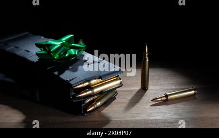 Magazines AR-15 haute capacité entièrement chargés sur une table comme un cadeau avec un arc vert sur le dessus. Banque D'Images